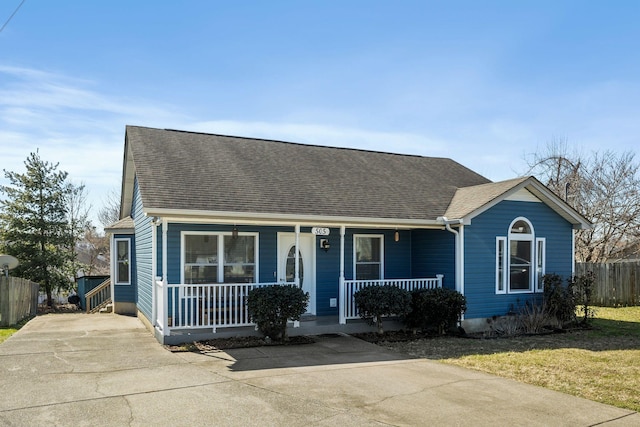 view of front of house with covered porch, a shingled roof, and fence