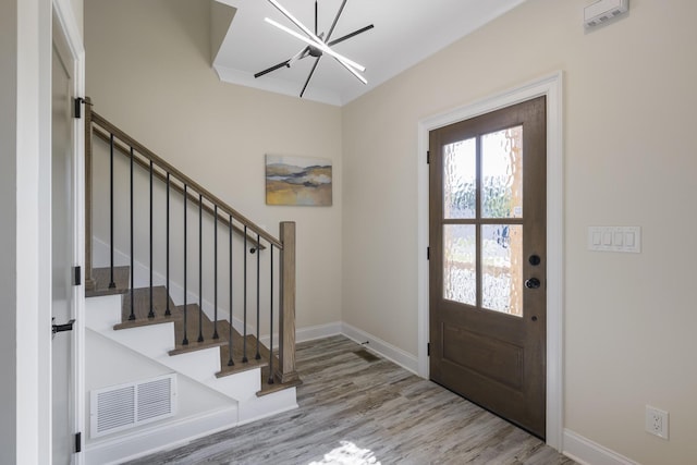 foyer featuring visible vents, baseboards, light wood-style flooring, stairs, and a chandelier