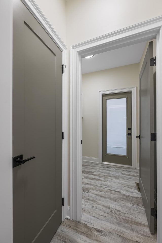 corridor with light wood-style floors and baseboards