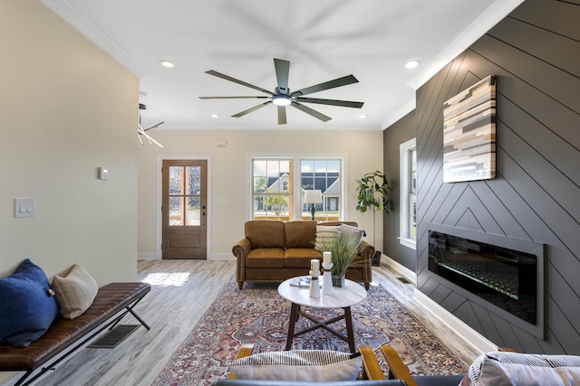 living room with recessed lighting, ornamental molding, a large fireplace, light wood-type flooring, and baseboards