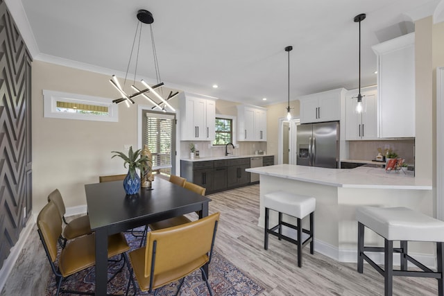 dining area with light wood-style floors, recessed lighting, crown molding, and baseboards