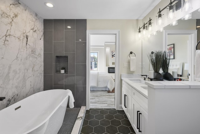 bathroom with double vanity, tile walls, a soaking tub, ensuite bath, and a sink