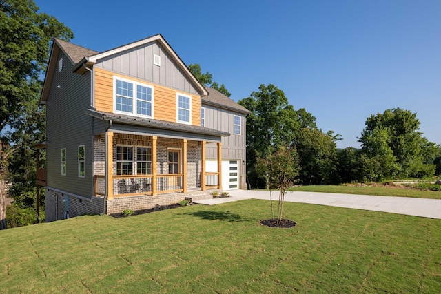 view of front of property featuring covered porch, brick siding, concrete driveway, board and batten siding, and a front yard