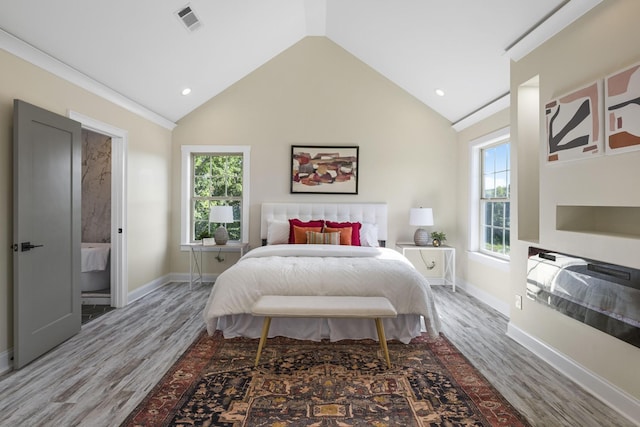 bedroom with vaulted ceiling, wood finished floors, visible vents, and baseboards