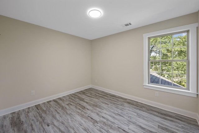 unfurnished room with baseboards, visible vents, and wood finished floors