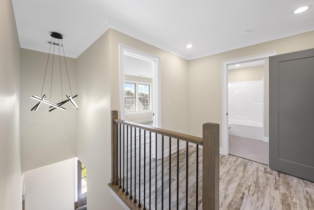 hallway with light wood-style floors, recessed lighting, and an upstairs landing