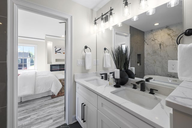 ensuite bathroom with a sink, double vanity, wood finished floors, and connected bathroom