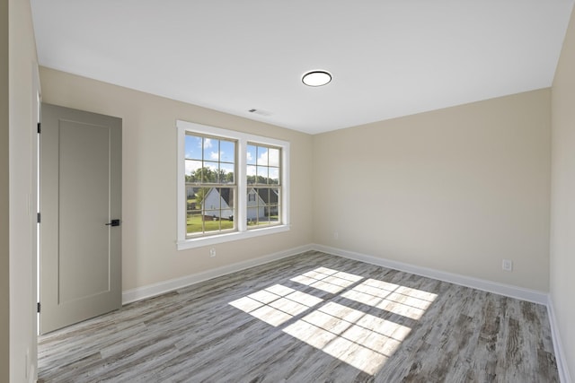 unfurnished room featuring light wood-style floors, visible vents, and baseboards