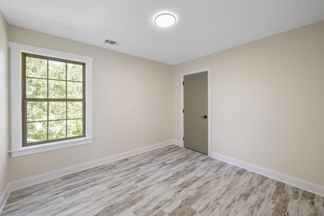 unfurnished room featuring baseboards, visible vents, and light wood-style flooring