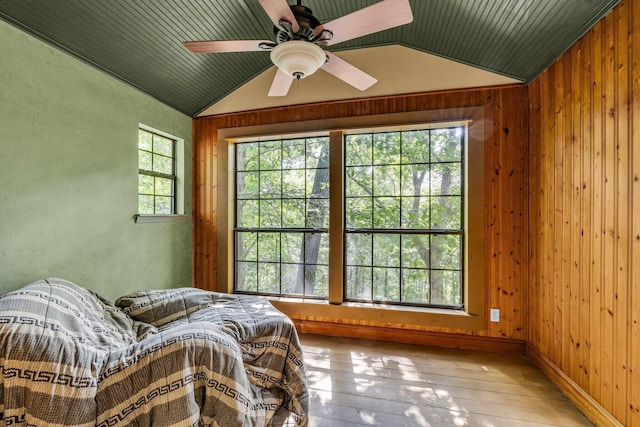 sitting room with vaulted ceiling, wood walls, hardwood / wood-style floors, and ceiling fan