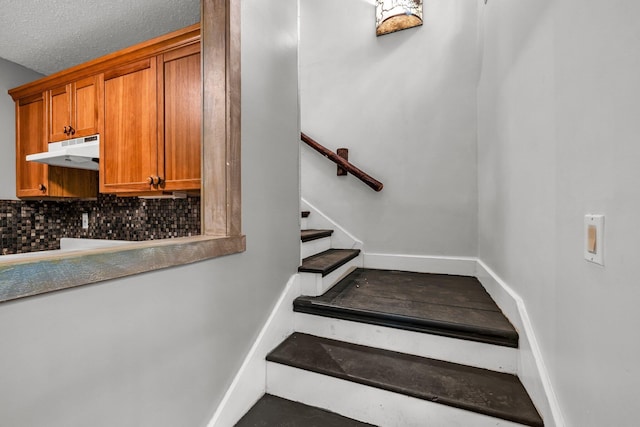 staircase with baseboards and a textured ceiling