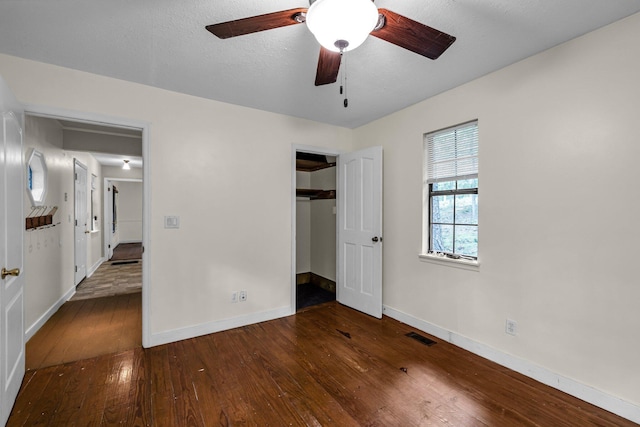 unfurnished bedroom featuring dark wood-style floors, a closet, a textured ceiling, and baseboards