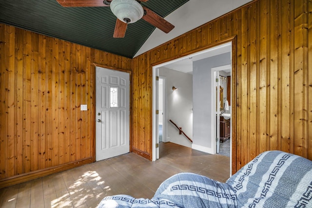 entryway with lofted ceiling, wood walls, hardwood / wood-style floors, and ceiling fan