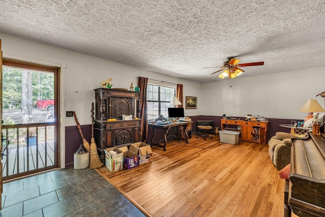 home office with a ceiling fan, a textured ceiling, and wood finished floors