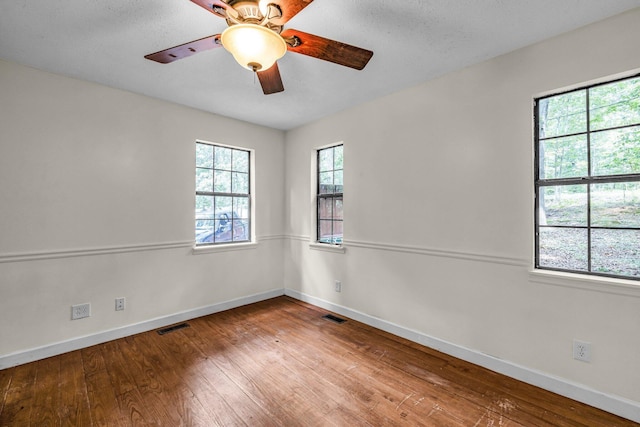 empty room featuring wood-type flooring, visible vents, and baseboards