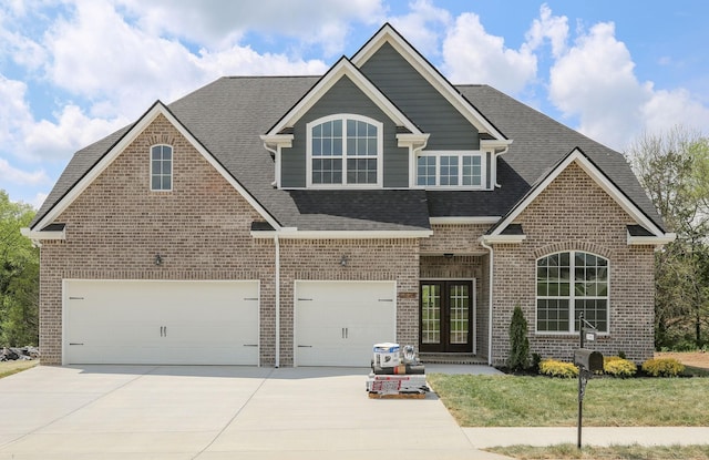 view of front of home featuring a shingled roof, concrete driveway, an attached garage, french doors, and brick siding