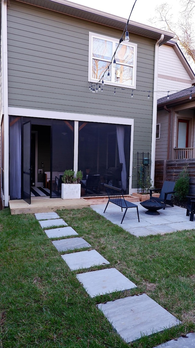 back of house featuring a patio, a fire pit, and a lawn