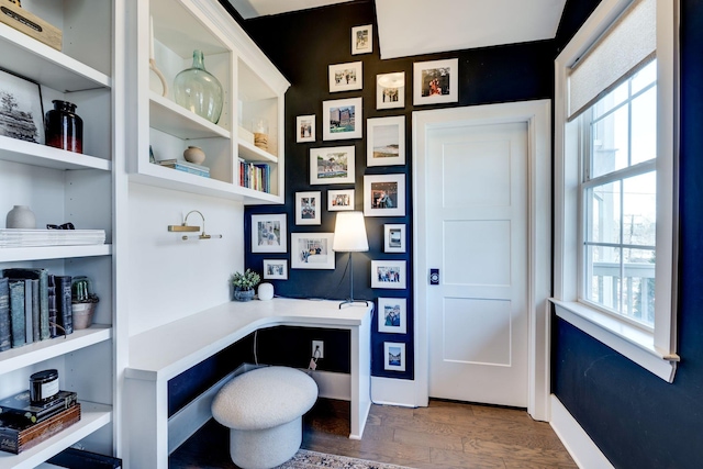 home office featuring baseboards, dark wood-type flooring, and built in study area