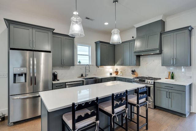 kitchen with visible vents, a center island, stainless steel appliances, light countertops, and a sink