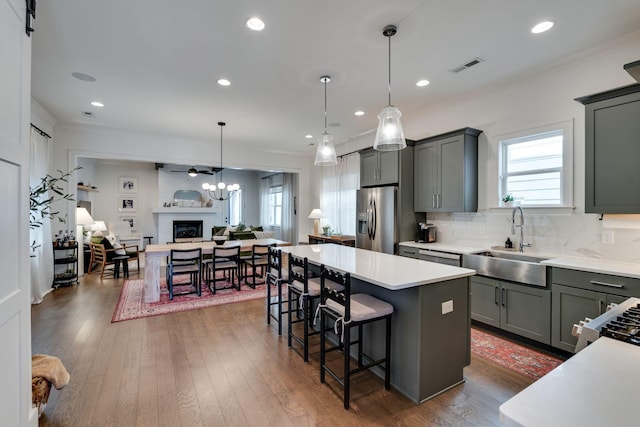 kitchen featuring open floor plan, a center island, light countertops, stainless steel refrigerator with ice dispenser, and a sink