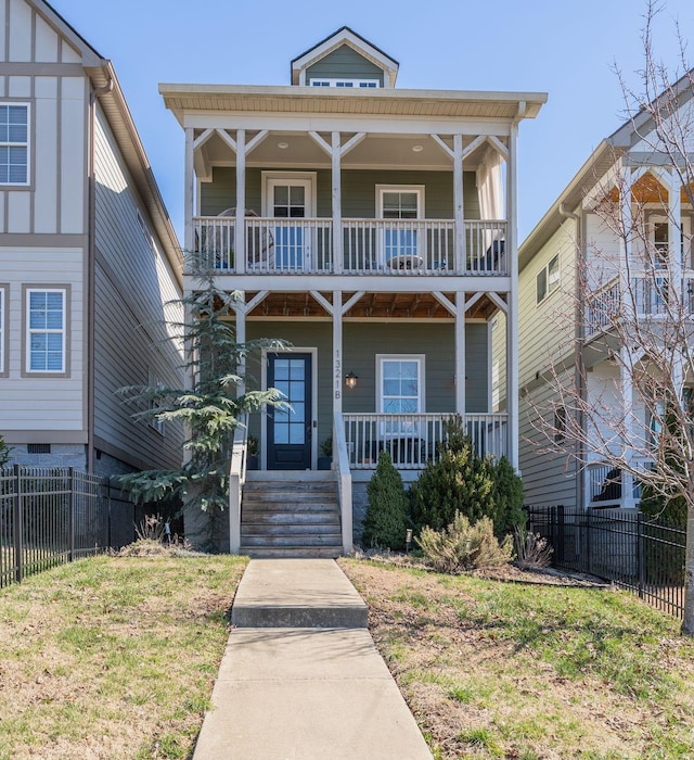 view of front facade with a porch, fence, a balcony, and a front lawn