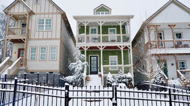 view of front of property featuring covered porch, board and batten siding, a balcony, and a fenced front yard