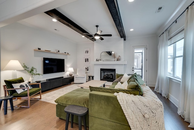 living room with a fireplace, wood finished floors, visible vents, a ceiling fan, and beam ceiling