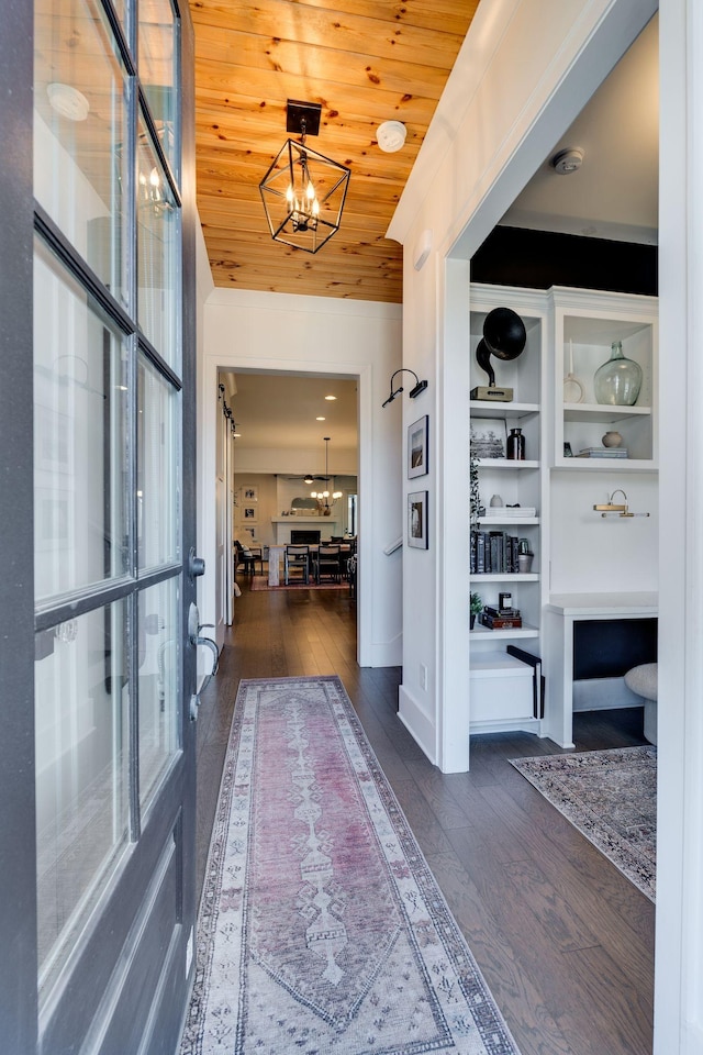 hall featuring a chandelier, dark wood-type flooring, and wood ceiling