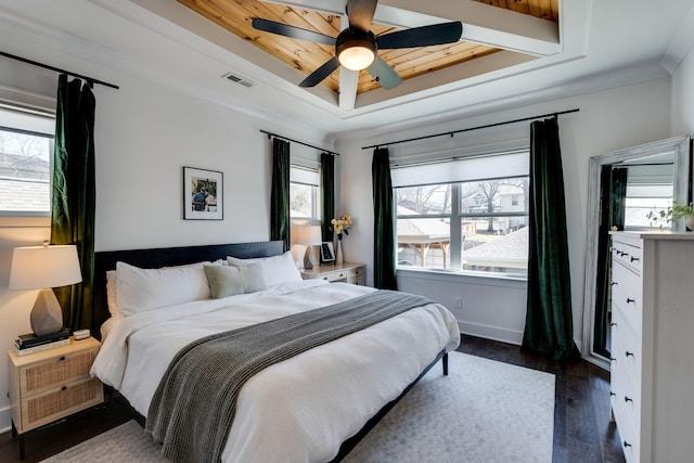 bedroom with a tray ceiling, dark wood finished floors, visible vents, a ceiling fan, and baseboards