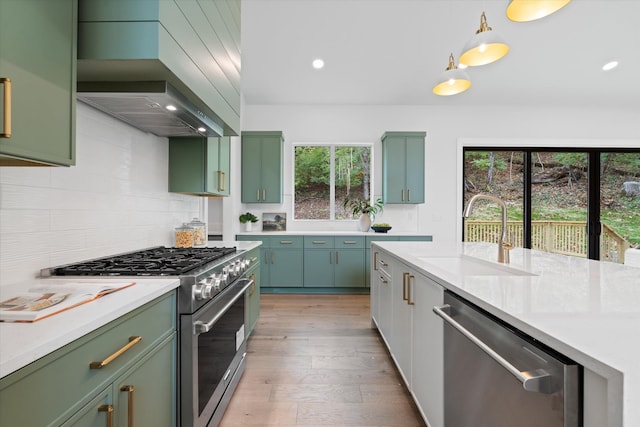 kitchen with extractor fan, a sink, appliances with stainless steel finishes, backsplash, and green cabinetry