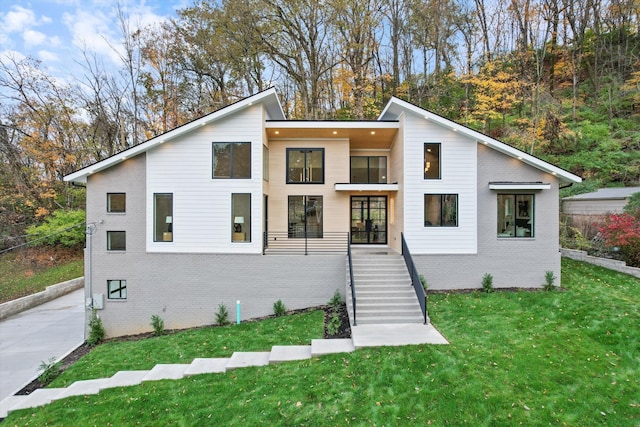 contemporary home with brick siding, stairway, and a front yard