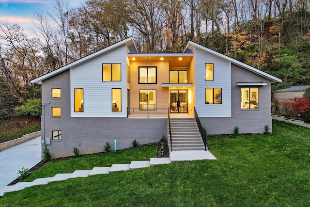 contemporary house featuring driveway, stairs, a front lawn, and brick siding