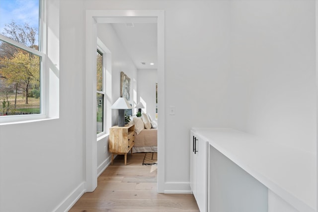 hallway featuring plenty of natural light, baseboards, and light wood-style flooring