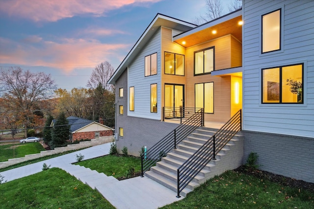 contemporary house featuring stairs, a front lawn, and brick siding