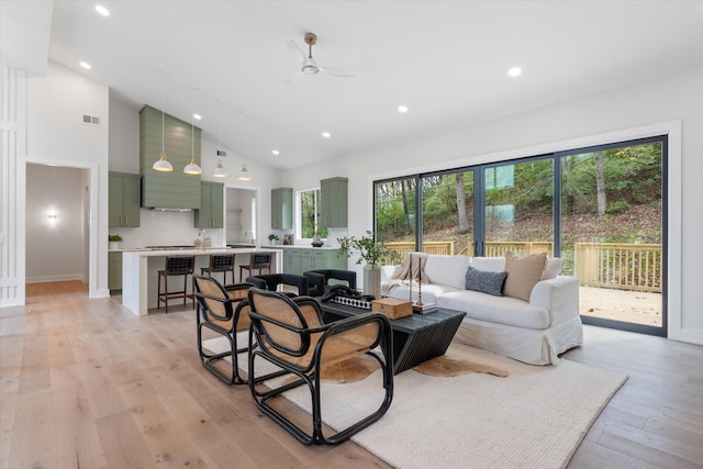 living area with high vaulted ceiling, recessed lighting, a ceiling fan, visible vents, and light wood-style floors