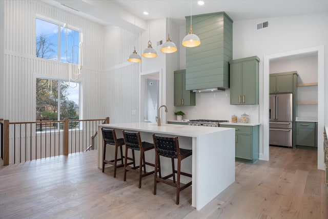 kitchen featuring green cabinets, high end fridge, light countertops, and visible vents