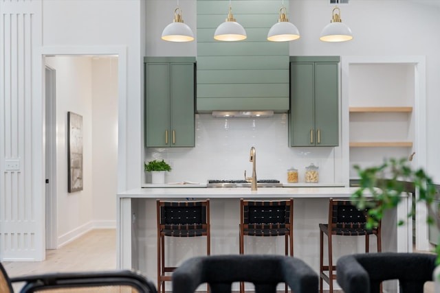 kitchen featuring light countertops, green cabinetry, decorative light fixtures, and a breakfast bar area