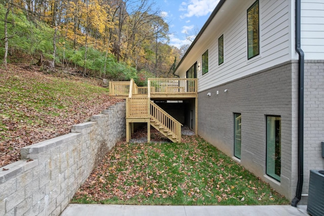 view of home's exterior with brick siding, a deck, and stairs