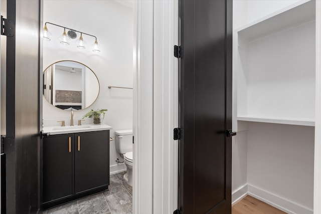 bathroom with toilet, vanity, and baseboards