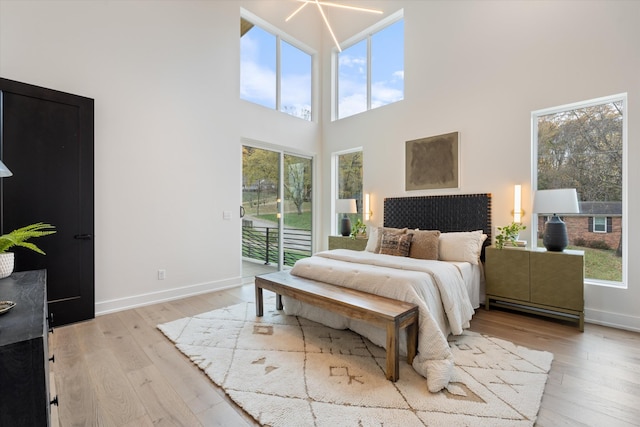 bedroom featuring access to exterior, baseboards, and light wood finished floors