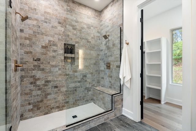 bathroom with a spacious closet, tiled shower, and a healthy amount of sunlight