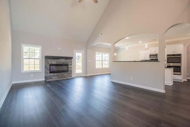 unfurnished living room with high vaulted ceiling, dark wood-type flooring, a fireplace, and a ceiling fan