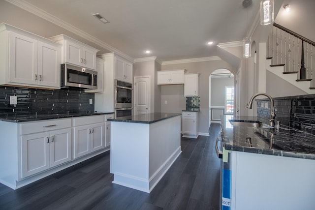 kitchen featuring arched walkways, a sink, visible vents, appliances with stainless steel finishes, and dark wood finished floors