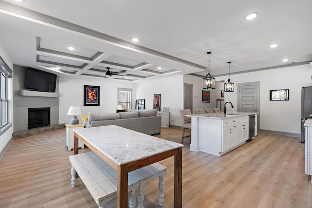 kitchen with a sink, white cabinets, open floor plan, hanging light fixtures, and an island with sink