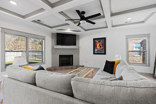 living room featuring visible vents, a fireplace, baseboards, and wood finished floors