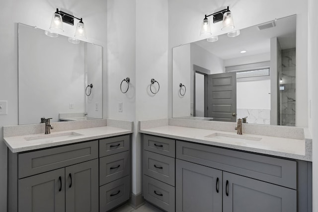 full bathroom featuring a stall shower, visible vents, two vanities, and a sink