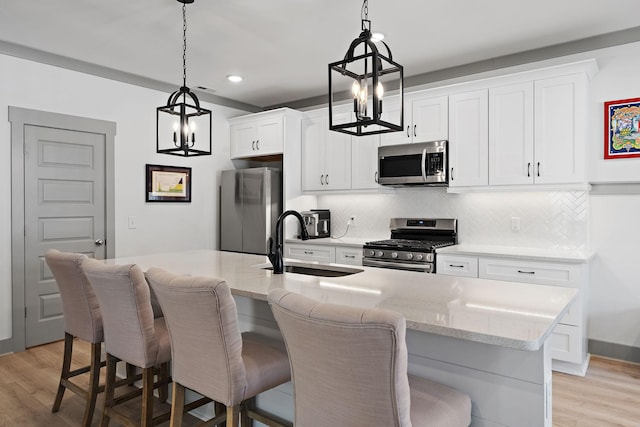 kitchen featuring an island with sink, appliances with stainless steel finishes, a kitchen breakfast bar, and a sink