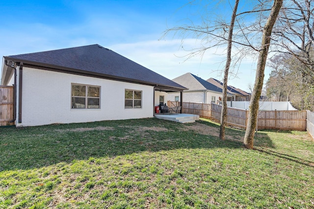 back of house with a yard, brick siding, a patio, and a fenced backyard