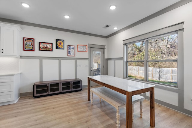 dining space with light wood-style floors, a decorative wall, and recessed lighting