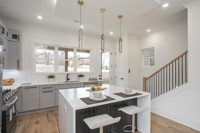 kitchen featuring crown molding, light countertops, appliances with stainless steel finishes, a sink, and a kitchen island